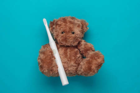 Teddy bear holds a toothbrush on a blue background. Teeth care. Top viewの写真素材