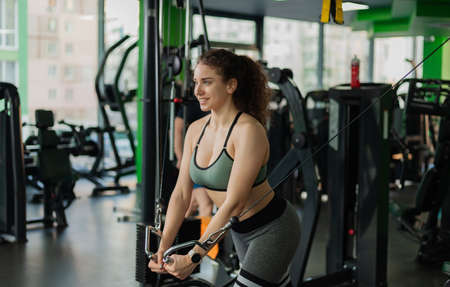 Young fit woman doing exercise in a crossover exercise machine. Healthy lifestyle concept. Bodybuilding and Fitnessの写真素材