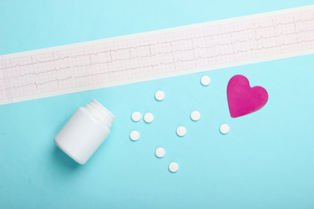 Diagnosis and prevention (treatment) of cardiovascular diseases. Heart cardiogram, pill bottle, decorative heart on a blue background. Healthy heart. Top viewの写真素材