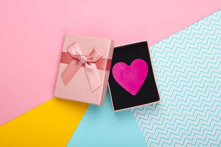 Gift box with bow and decorative heart on a colored background. St. Valentine's Day. Pastel color trend. Top viewの写真素材