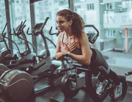 Young cheerful woman in sportswear doing hyperextension exercise in the gym