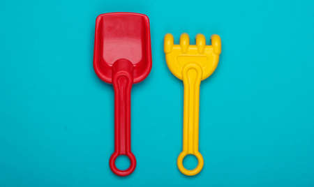 Children's rake and shovel for a sandbox or beach on blue studio background. Top view