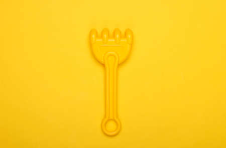 Children's rake for a sandbox or a beach on a yellow studio background. Top viewの写真素材