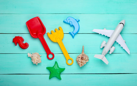 Flat lay composition of beach vacation, resort and travel. Children's beach toys, airplane figurine, shells on a blue wooden background. Top viewの写真素材