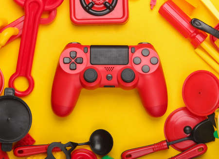 Gamepad and many children's toys on yellow background. Gaming, childhood concept. Top view