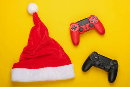 Gamepads with santa hat on a yellow background. Top view