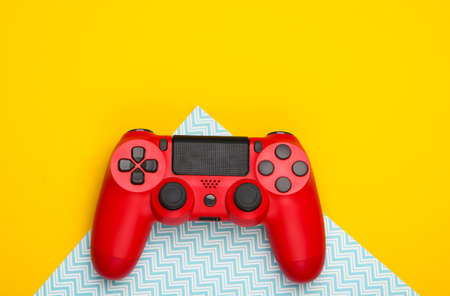 Red gamepad on yellow blue background. Gaming, leisure and entertainment concept. Top view