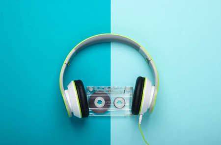 Stylish wired stereo headphones with audio cassette on blue background. Music lover. Retro 80s. Top view.の写真素材