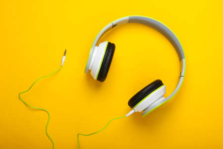 Stylish wired stereo headphones on yellow background. Music lover. Gadgets. Top view.の写真素材