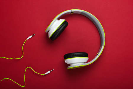Stylish wired stereo headphones on red background. Music lover. Gadgets. Top view.の写真素材