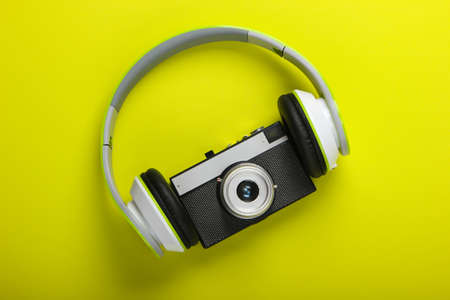 Stylish wired stereo headphones with retro camera on green background. Music lover. Travel concept. Retro 80s. Top view.の写真素材