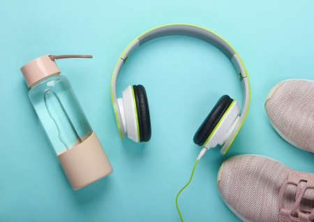 Flat lay composition of sports and fitness. Running shoes, headphones, bottle of water on blue background. Top viewの写真素材