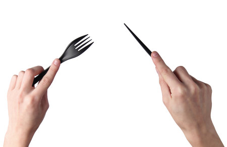 Female hands hold black plastic knife with a fork isolated on white backgroundの写真素材