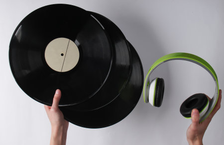 Hands hold vinyl records and headphones on a white background. Retro media, 70sの写真素材