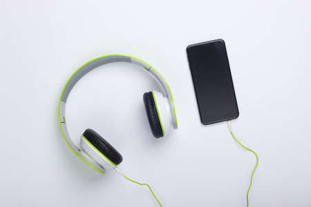 Stylish wired stereo headphones with smartphone on white background. Music lover. Top view. Minimalismの写真素材