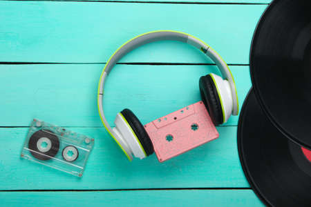 Stereo headphones with audio cassette, vinyl records on blue wooden table. Music lover. Retro 80s. Top view.の写真素材