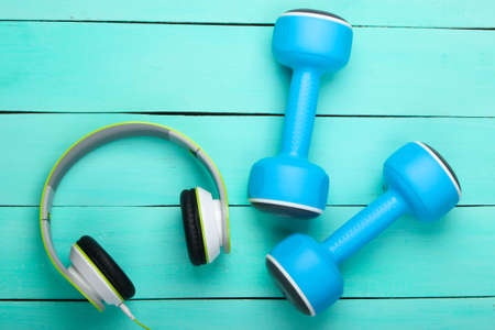 Dumbbells and headphones on blue wooden table. Sports and fitnessの写真素材