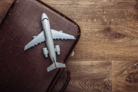Travel concept. Old luggage and airplane figurine on wooden floor. Flight voyage, trip, journey. Flat lay composition. Top viewの写真素材