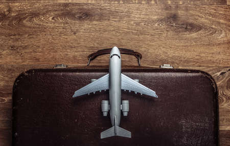 Travel concept. Old luggage and airplane figurine on wooden floor. Flight voyage, trip, journey. Flat lay composition. Top viewの写真素材