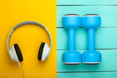 Dumbbells and headphones on blue wooden table. Sports and fitness
