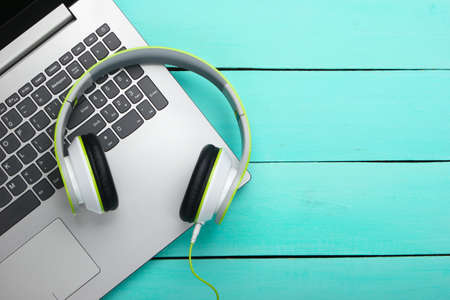 Laptop with headphones on blue wooden background. DJ, gaming, entertainment or leisure concept. Top view. Flat layの写真素材