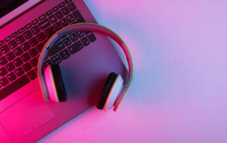DJ or gaming concept. Laptop and headphones with neon blue-pink light. Top viewの写真素材