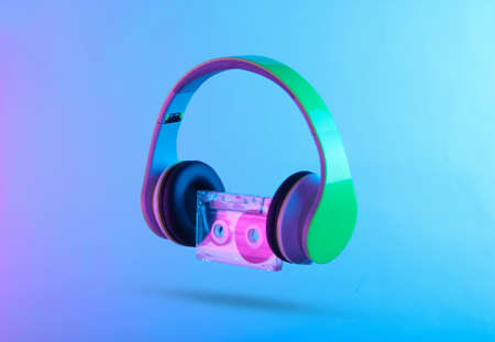 Stereo headphones with audio cassette. Neon vibrant pink-blue light. Gradient glow. Retro wave 80s