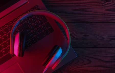 DJ or gaming concept. Laptop and headphones with neon blue-red light. Top viewの写真素材