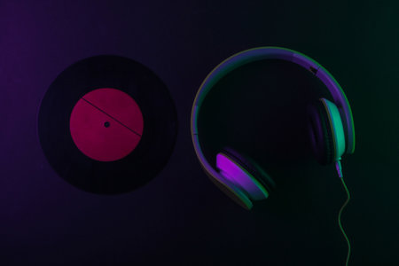 Retro stereo headphones with vinyl record. Neon purple green light. Gradient glow. 80s. Top viewの写真素材