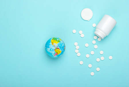 Global epidemic, pandemic concept. Globe with a bottle of pills on a blue background.の写真素材
