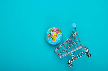 Concept of shopping and global market. Shopping trolley with a globe on a blue background. Top viewの写真素材