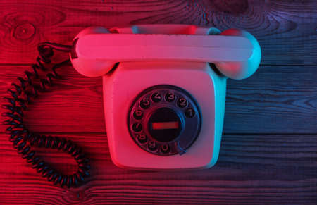 Retro rotary telephone on a wooden background with red-blue neon light Top viewの写真素材