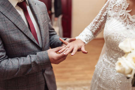 The groom puts a golden ring on the bride's finger. Wedding ceremonyの写真素材