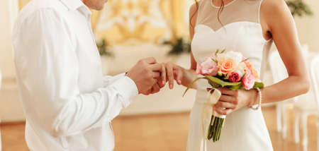 The groom puts a golden ring on the bride's finger. Wedding ceremonyの写真素材