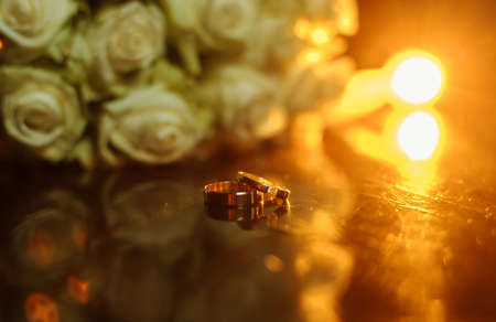 Wedding bouquet of white roses with golden rings close-up.