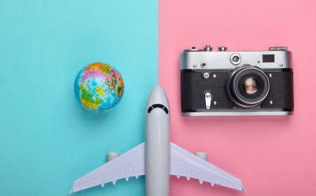 Tourism and travel concept. Globe, camera and passenger plane figurine on pink blue pastel background. Top view. Flat layの写真素材