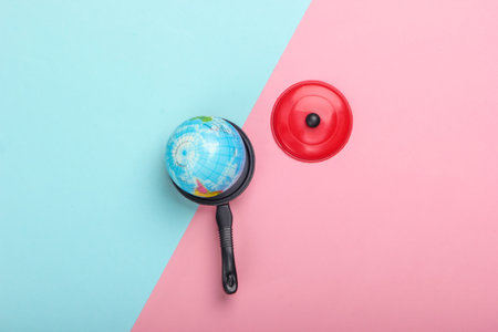 Global warming concept. Mini globe in a toy pan on a blue-pink pastel background. Top view. Minimalism. Climatic problems of our time. Top viewの写真素材
