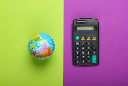 Calculator and globe on purple green background. Top viewの写真素材