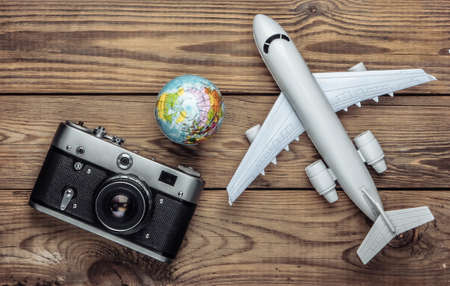 Tourism and travel concept. Globe, camera and passenger plane figurine on wooden tabe. Top view. Flat layの写真素材