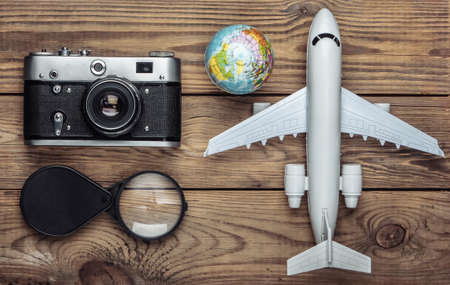 Tourism and travel concept. Globe, magnifier, camera and passenger plane figurine on wooden table....