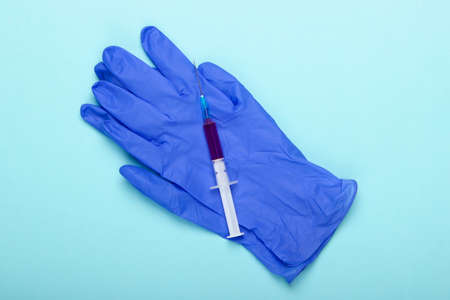 Blue latex gloves and syringe on a blue background. Vaccination. Top viewの写真素材