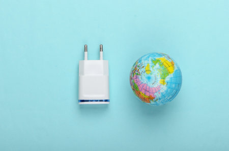 charging the energy of the planet. Charger and globe on a blue pastel background. Top view