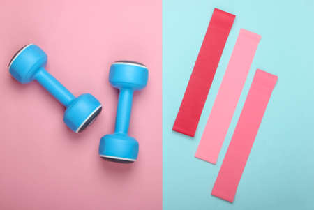 Dumbbells with fitness elastic bands on pink blue pastel background. Top view, flat layの写真素材