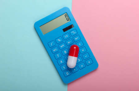 Calculation of the cost of medical expenses. Calculator and pill on a blue-pink pastel background. Top view. Minimalismの写真素材