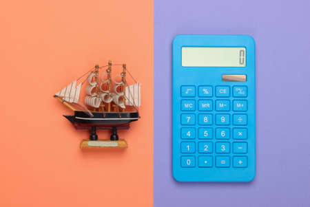 Calculation of the cost of a cruise, travel or sea delivery. Calculator with a ship figure on orange purple background. Top viewの写真素材