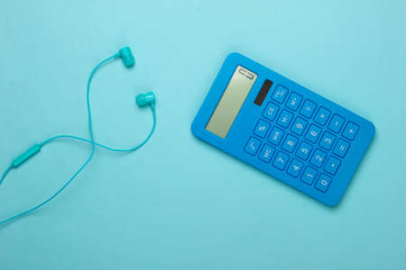 Earphones with calculator on blue background. Top viewの写真素材