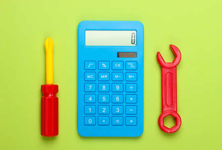 Calculation of the cost of repair work. Calculator and toy wrench and screwdriver on green background. Top viewの写真素材