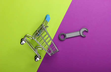 Supermarket shopping trolley with toy wrench on purple green background. Top viewの写真素材