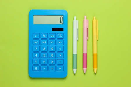 Blue calculator with colored pens on a green background. Top view. Office tools. Economistの写真素材
