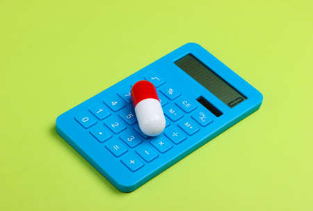 Calculation of the cost of medical expenses. Calculator and pill on green background.の写真素材